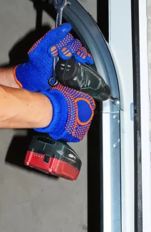 Worker uses power drill to install metal frame in garage during home improvement project