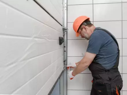 Expert worker installs garage door hardware in a modern indoor setting during daylight hours