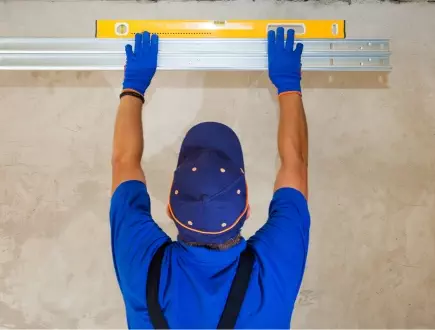 Worker using level tool to install wall panels in a construction project Expert installation of garage doors