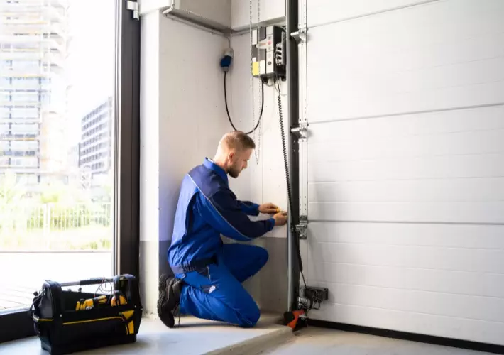 Technician repairs garage door mechanism in modern building during daylight Expert garage door repair services for homes