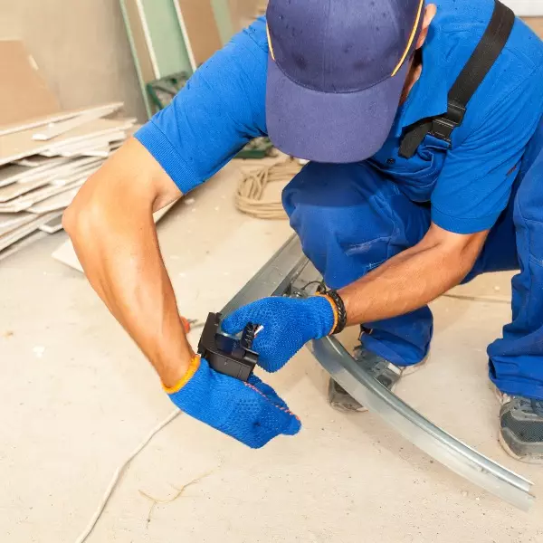 Worker measures and adjusts metal strip while constructing interior space using modern tools and techniques Worker measures and adjusts metal strip while constructing interior space using modern tools and techniques