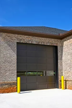 Brown garage door opens to a bright exterior under a clear blue sky at a modern building High-performance commercial garage door