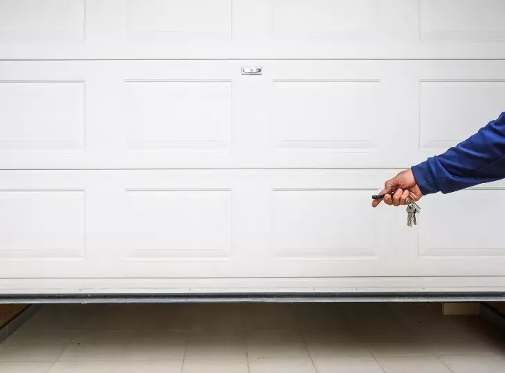 Man holding keys near a closed garage door on a bright day while preparing to park a vehicle Modern garage door opener with advanced features
