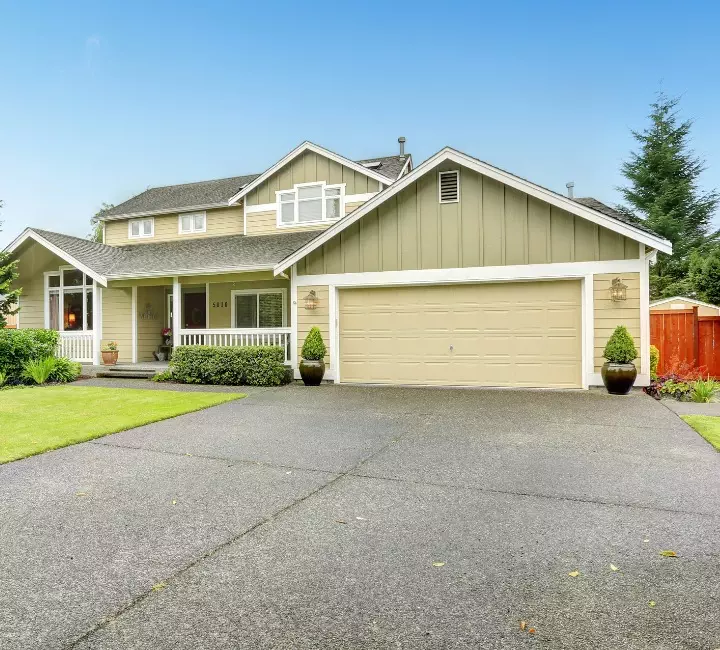 Family home with a welcoming front yard and spacious driveway located in a suburban neighborhood Residential garage door for safety and performance